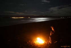 A camp fire, Húsavík across the bay
