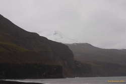Snowy mountains over sea cliffs
